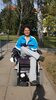 SHG Schlaganfallsprecherin Nicole Ulbrich präsentiert das WIR HILFT Selbsthilfelogo Logo auf ihrem Rollstuhl
