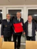 Verabschiedung von Kreisbrandmeister Frank Jahraus durch Kommandant Peter Fischer und Bürgermeister Reinhold Möhrle, Bürgermeister übergibt ein Sitzkissen als Geschenk.