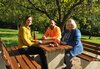 An der neuen Sitzgruppe unter dem alten Nussbaum erläutern Erika Hütten (re.) und Anna-Lena Tsutsui mit Bauhof-Chef Matthias Stark die Aufwertung des Geländes.